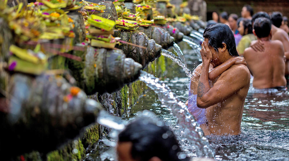 Drikk det hellige vannet ved Tampaksiring templet i Bali 